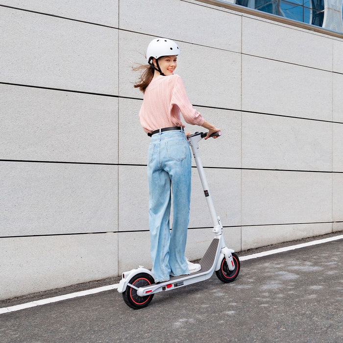 Person riding a scooter with a helmet on a city street.