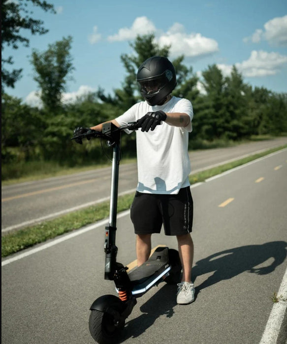 Person riding a scooter on a road with trees in the background