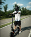Person riding a scooter on a road with trees in the background
