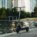 Electric scooter by a body of water with city skyline in the background
