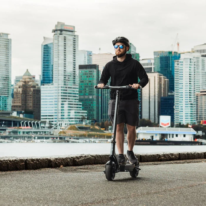 Person riding an electric scooter with a city skyline in the background