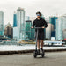 Person riding an electric scooter with a city skyline in the background