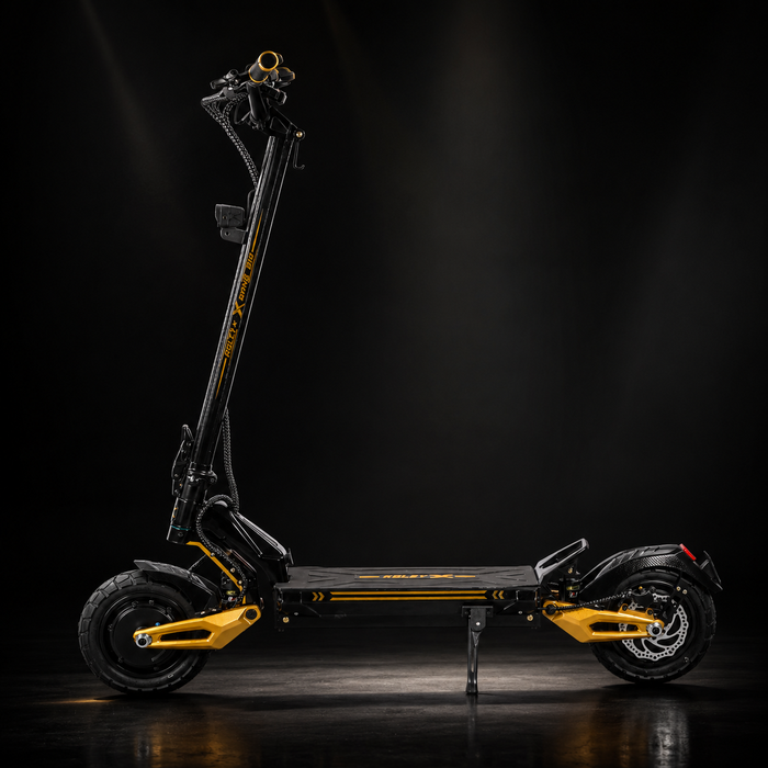 A black and yellow electric scooter photographed in a dark studio setting, shown in full side view on its kickstand with dramatic spotlighting.