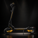A black and yellow electric scooter photographed in a dark studio setting, shown in full side view on its kickstand with dramatic spotlighting.